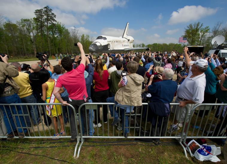 Spectators watch as the Space Shuttle Discovery is rolled towards the Udvar-Hazy Center.