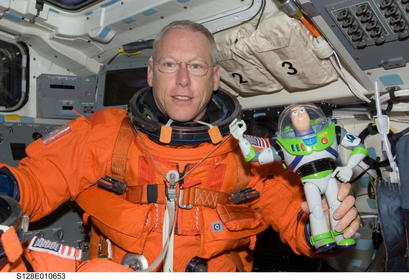 Patrick G. Forrester, an astronaut, holds a Buzz Lightyear figure in his hand while aboard a space shuttle.