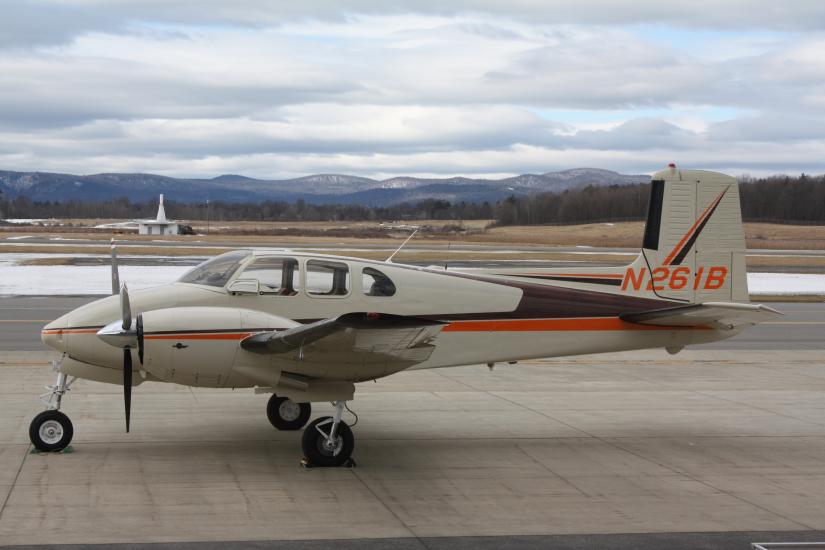 Side view of tan aircraft with orange and brown accent colors and two engines. Registration number N261B is painted in orange on the vertical stabilizer.