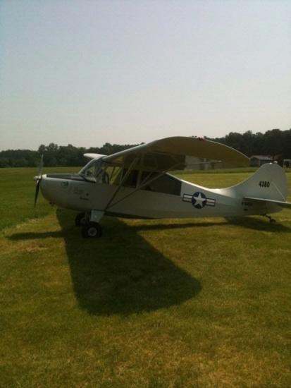 Side view of silver monoplane with single engine. A white and blue star emblem is painted behind the cockpit near the rear of the fuselage.