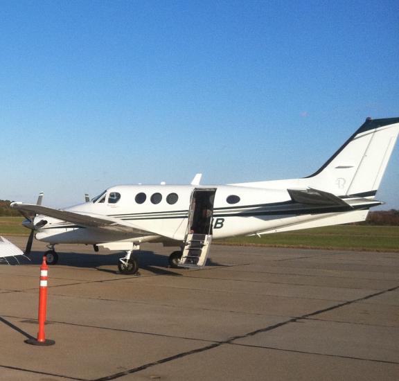 Side view of white aircraft with open door allowing interior access in the middle of the fuselage.