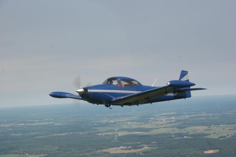 Side view of blue monoplane with a single engine in flight.