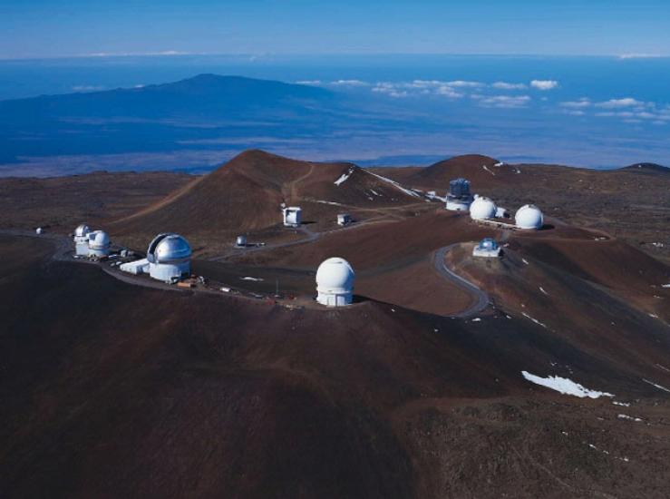 Multiple observatories with sphere-shaped domes are scattered across Mauna Kea, a volcano in Hawaii.