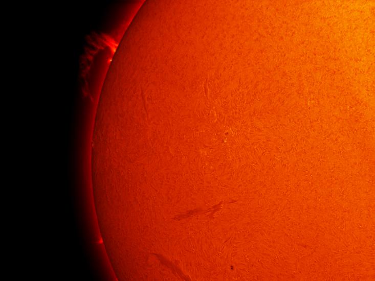 Partial disk view of the Sun's chromosphere, which focuses on one prominence rising from the Sun's surface.