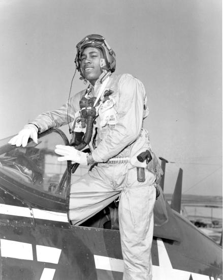 General Frank E. Petersen, an African-American Marines aviator, poses as he steps into a plane. He is wearing pilot gear.