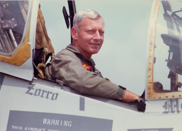 John R. Dailey, a white male general for the U.S. Marines, smiles from the cockpit of a plane.