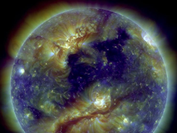 A partial view of the Sun with multiple large filaments visible as reddish-brown lines. Yellow and white spots around the sun represent areas with stronger magnetic fields.