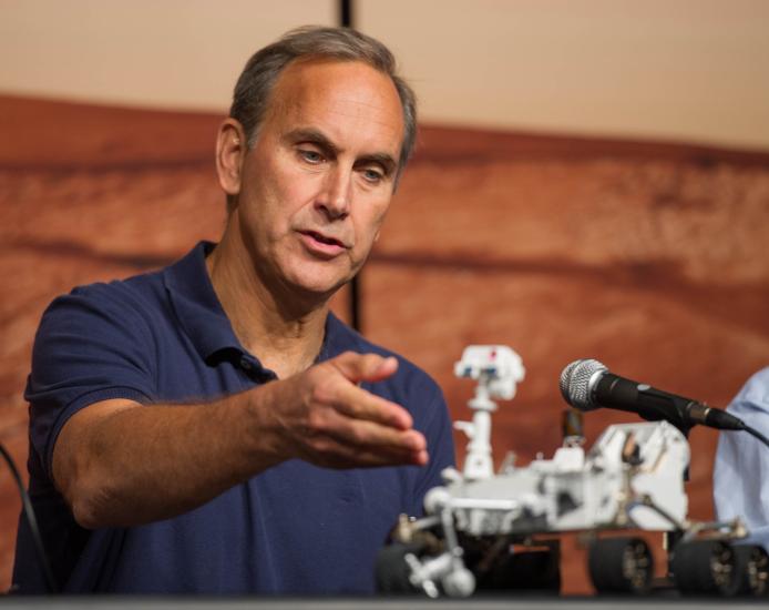 A white man directs his hand towards a Rover model.