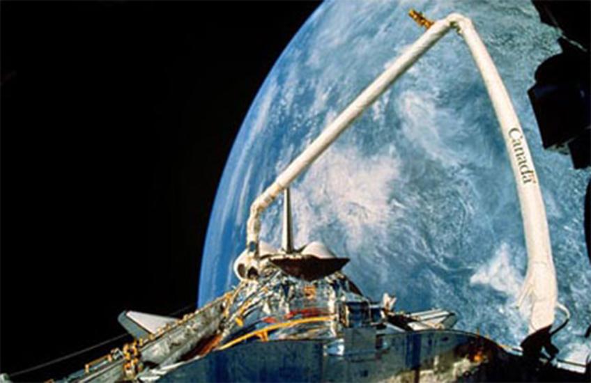 A view of the Hubble Space Telescope's payload bay and Canadarm with the backdrop of Earth.