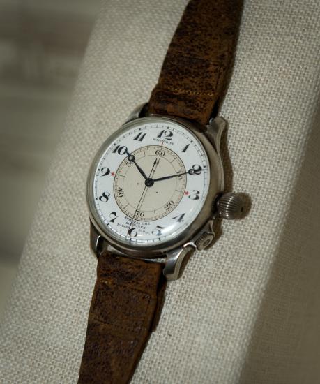 An analog watch with a brown leather watchband.