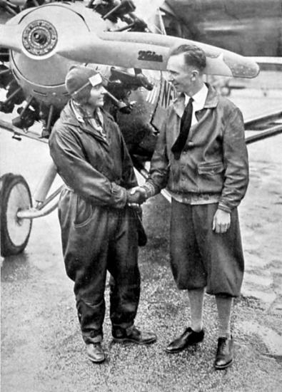 Thea Rasche, a white female pilot, holds hands with Clarence Chamberlin, a white male pilot.