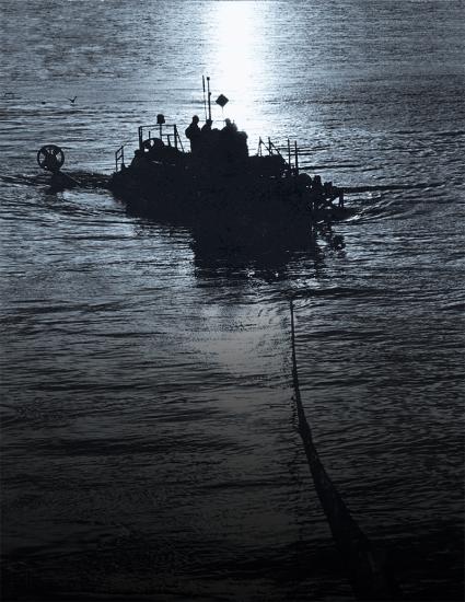 A silhouette of a boat being towed during nighttime hours