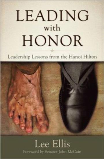 Cover of a book titled "Leading with Honor: Leadership Lessons from the Hanoi Hilton". Below the title is an image of two feet. The right foot is bare without any shoes whereas the left foot is wearing a black dress shoe.