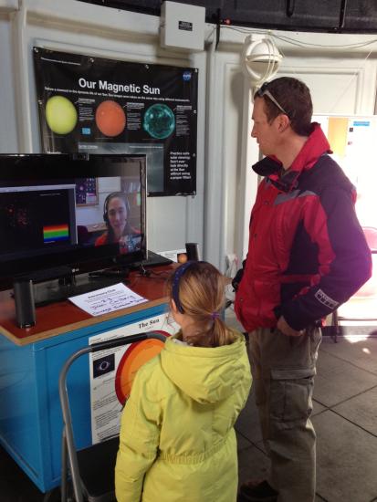 Two visitors speak with an astronomer through video chat in the Museum's observatory.