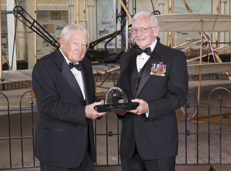 Joseph Sutter and Gen. Jack Dailey, both white men, pose for a photo as Joseph Sutter accepts a trophy.