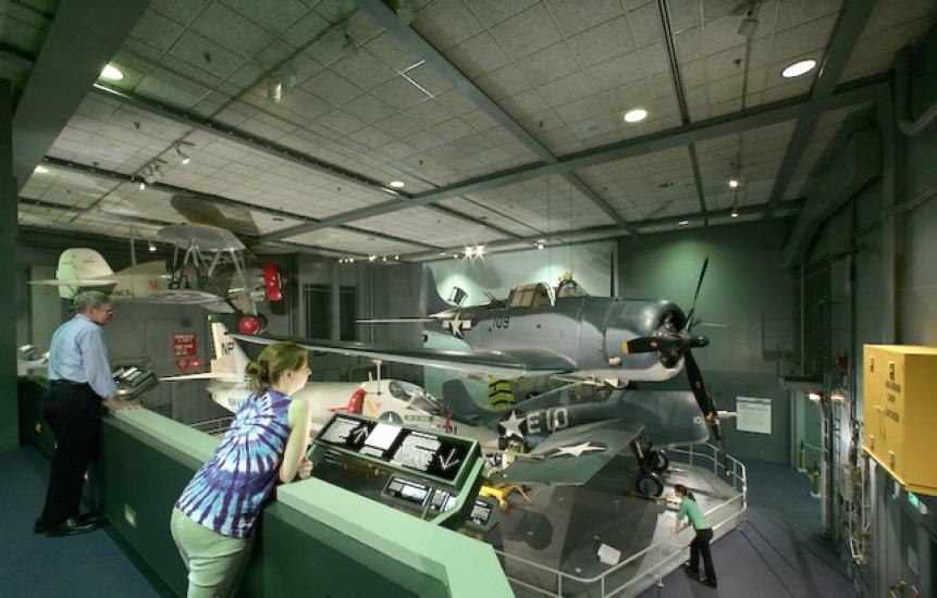 A visitor leans to look closer at an artifact in the Sea-Air Operations Gallery.