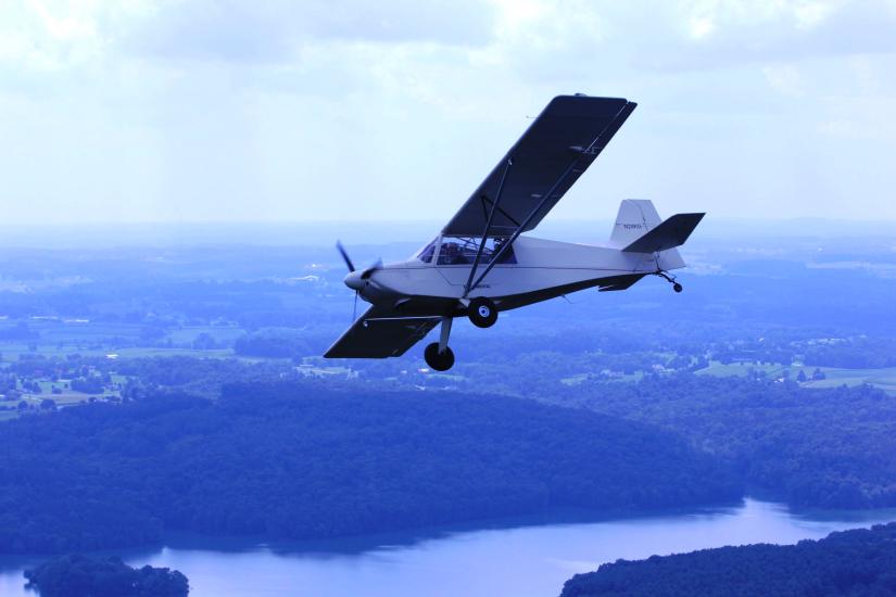 Side view of a white monoplane with one engine in flight. 