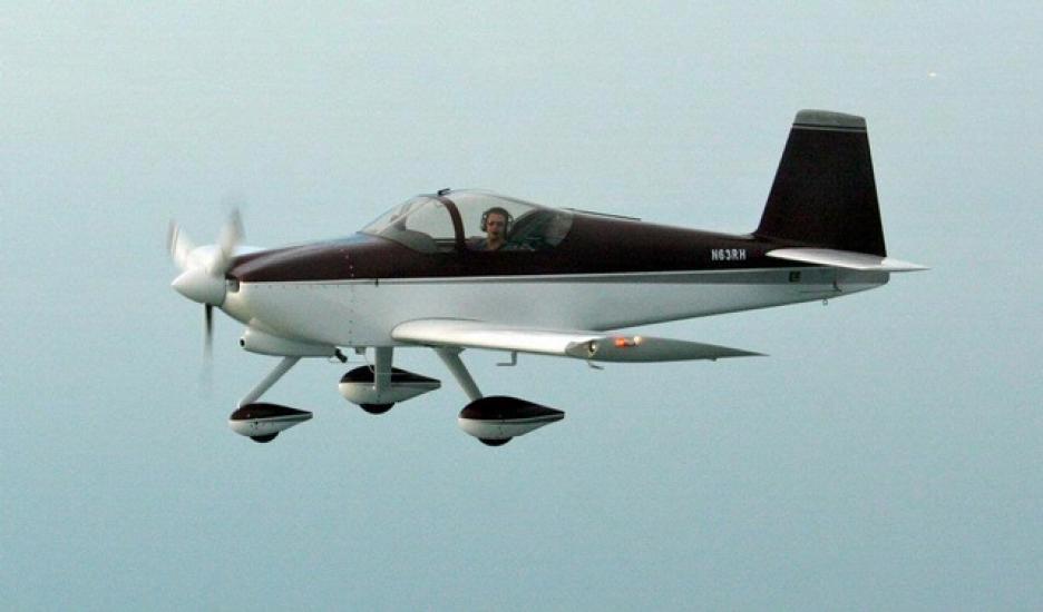 Side view of black and white monoplane in flight with a single engine and fixed landing gear.