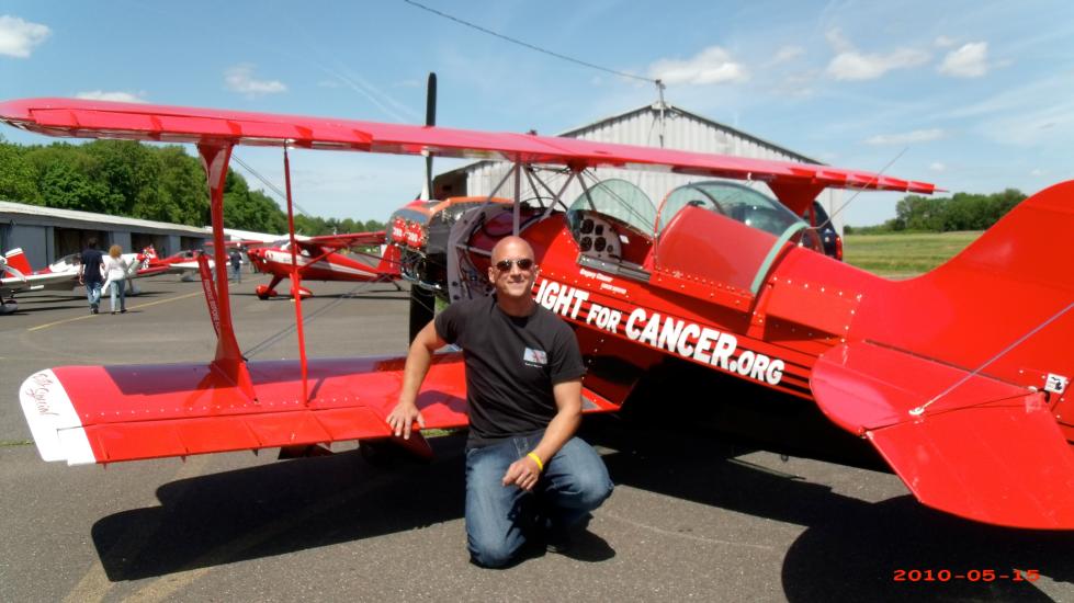 Back view of red biplane with a person standing in front of the wing.