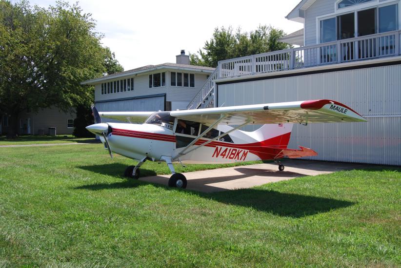 Side view of white and red monoplane with single engine. Registration number N318KM is painted in red near the rear of the fuselage.