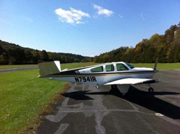 Side view of white monoplane with single engine and black and yellow accent colors. The registration number "N7941R" is written in black near the rear fuselage.