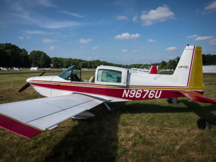 Side view of white and red monoplane with one engine. Registration number "N9676U" is painted in white near the rear of the fuselage.