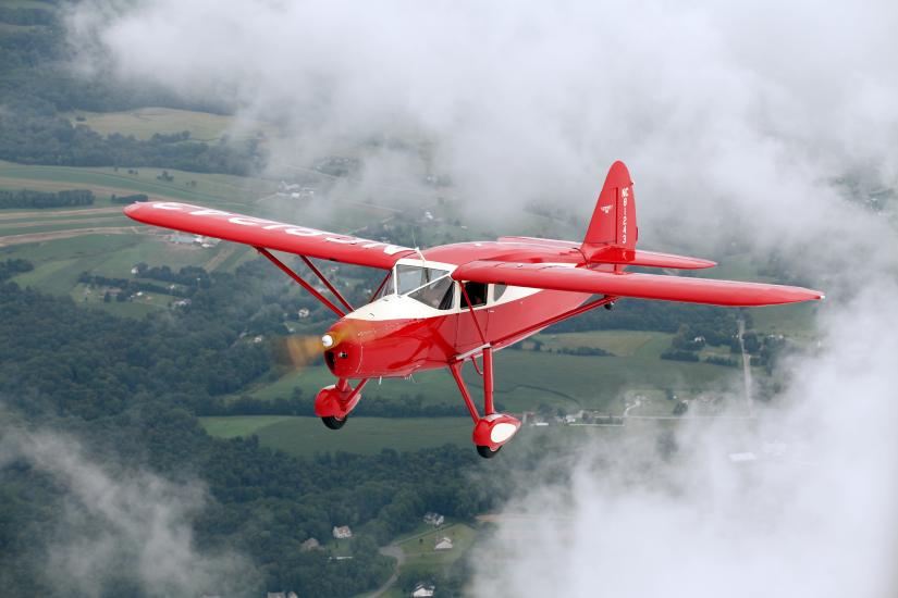 Front view of red and white monoplane with one engine and fixed landing gear.