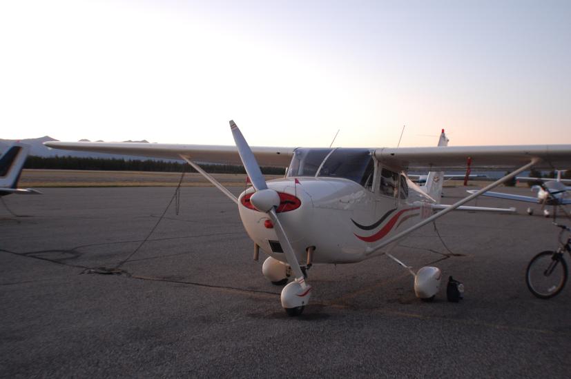 Front view of a white monoplane with a single engine and fixed landing gear.