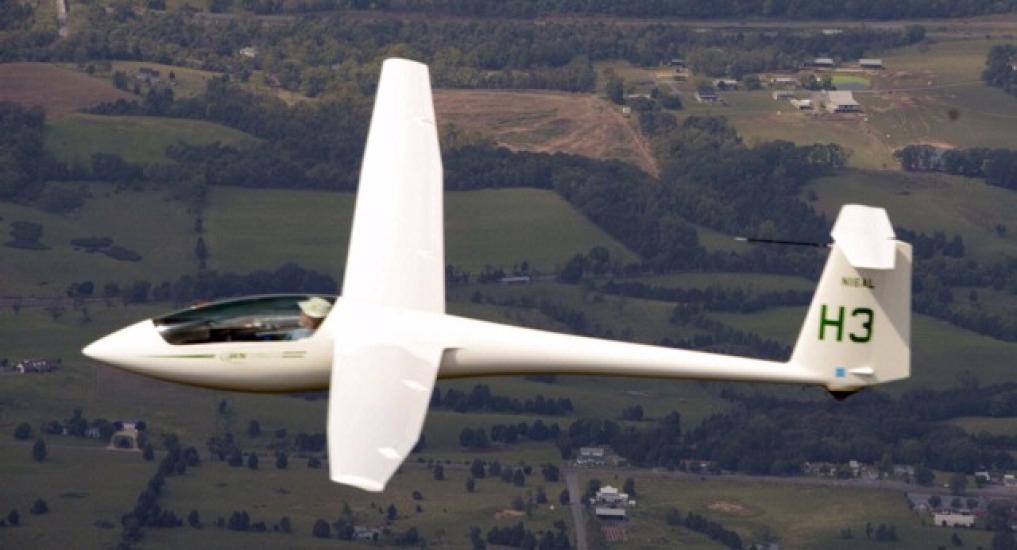 Side view of white glider aircraft with notably long wings.