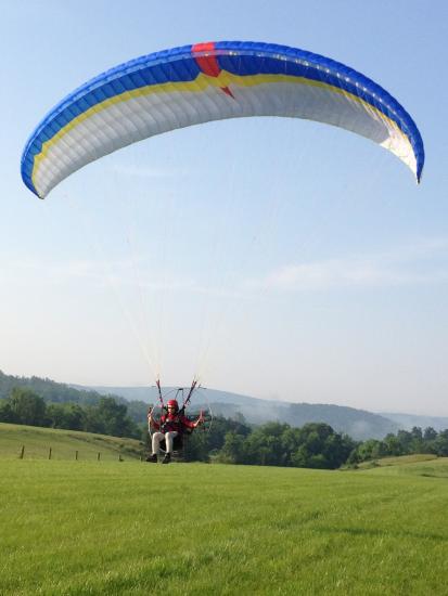 Front view of one-person paraglider with blue, yellow, and white fabric.