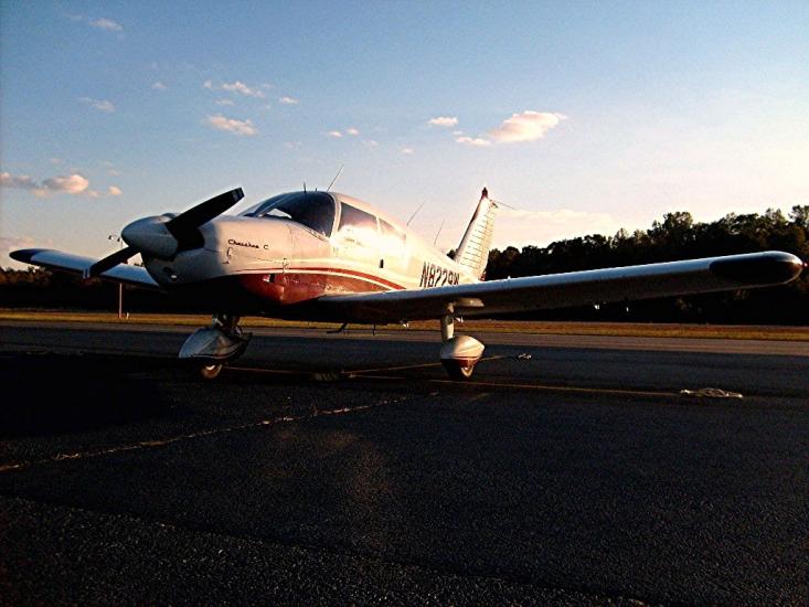 Front view of white and red-colored monoplane with single engine and fixed landing gear.