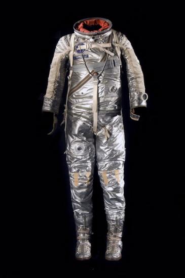 Silver-colored spacesuit with multiple tubes used for life support as well as openings for a helmet and gloves.