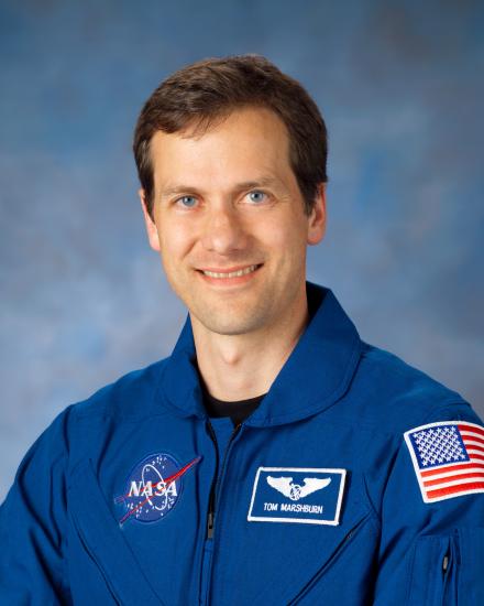 Dr. Thomas Marshburn, an astronaut, sits for an official portrait wearing blue NASA flight gear.