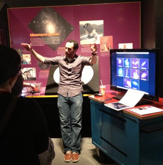 A museum expert discusses astronomy with visitors inside a museum gallery.