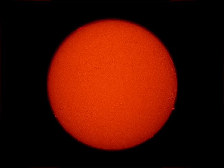 Disk view of the Sun's atmosphere with the remnants of a sunspot cluster visible as phages (lighter colored clouds) on the far bottom right side of the disk.