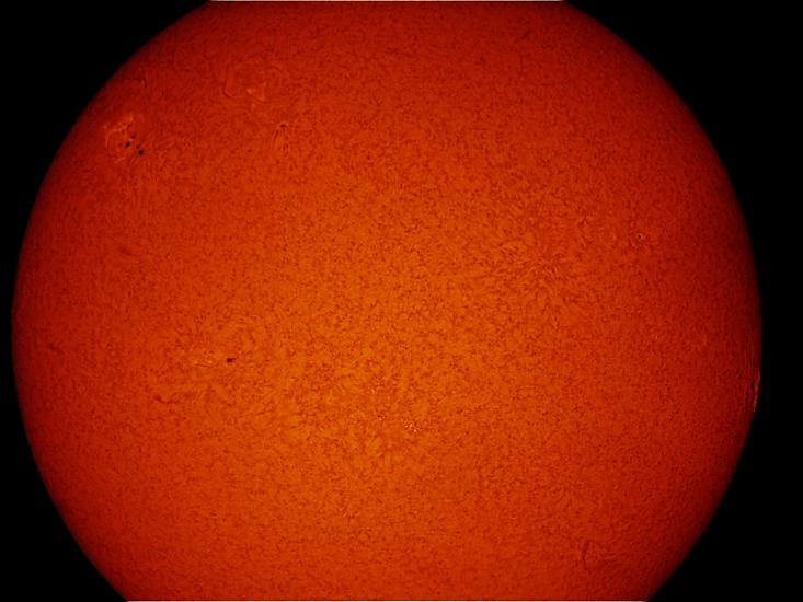 Partial disc view of the Sun's atmosphere. A sunspot cluster is visible on the upper left quadrant of the disk.