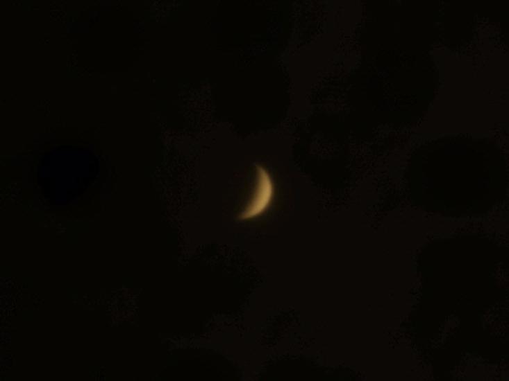 View of Venus in a crescent phase during daytime hours.