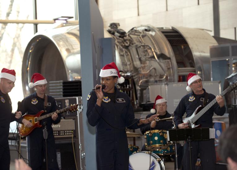 A group of U.S. Air Force musicians perform at the Museum. They are wearing red and white Santa hats.