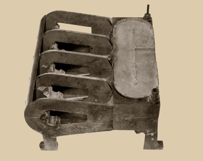 An aluminum, gray-colored engine part with four sections on one side and a covered section on the other side.