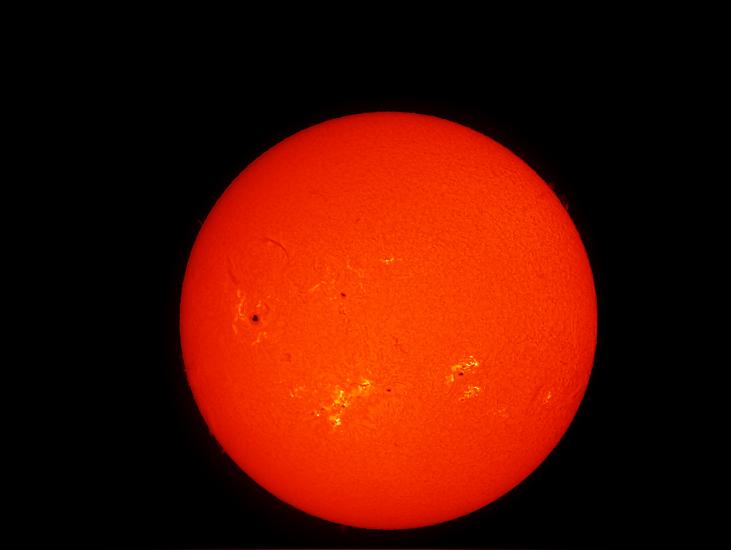 Disk view of the Sun's atmosphere. Sunspots (seen as dark spots) and phages (lighter-colored clouds) are visible on the disk.