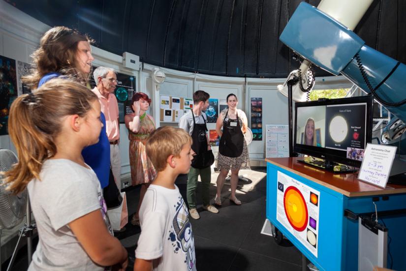 Museum visitors video chat with an expert on astronomy inside the Museum's observatory.