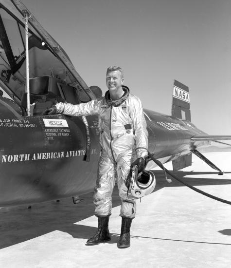 Joe Walker, a white man, stands next to a record-breaking experimental rocket plane that he flew.