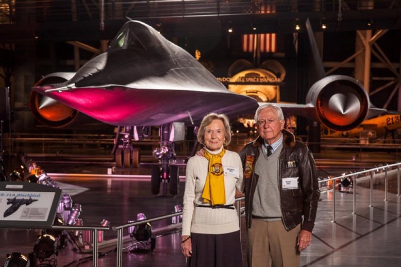 Richard and Anne Jones, a couple consisting of a white man and woman, pose together in front of the Blackbird on display in the Museum.