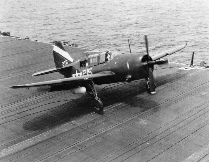 Side view of a monoplane with one engine parked on an naval aircraft hangar. 