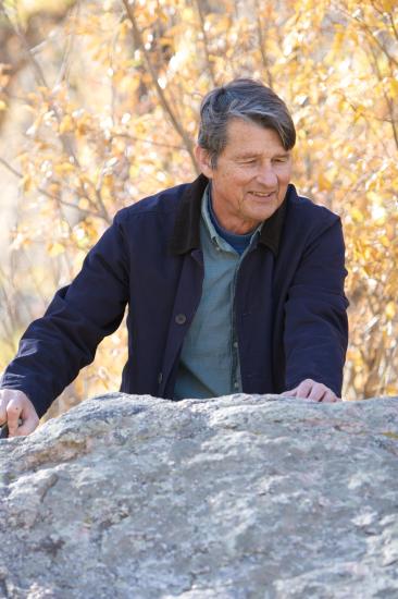 Karl G. Hufbauer, a man, stands outside behind a rock.