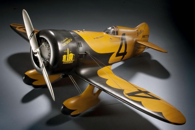 Yellow and black monoplane model with one engine and fixed landing gear. The number four is painted numerically on the left wing and on the side behind the cockpit