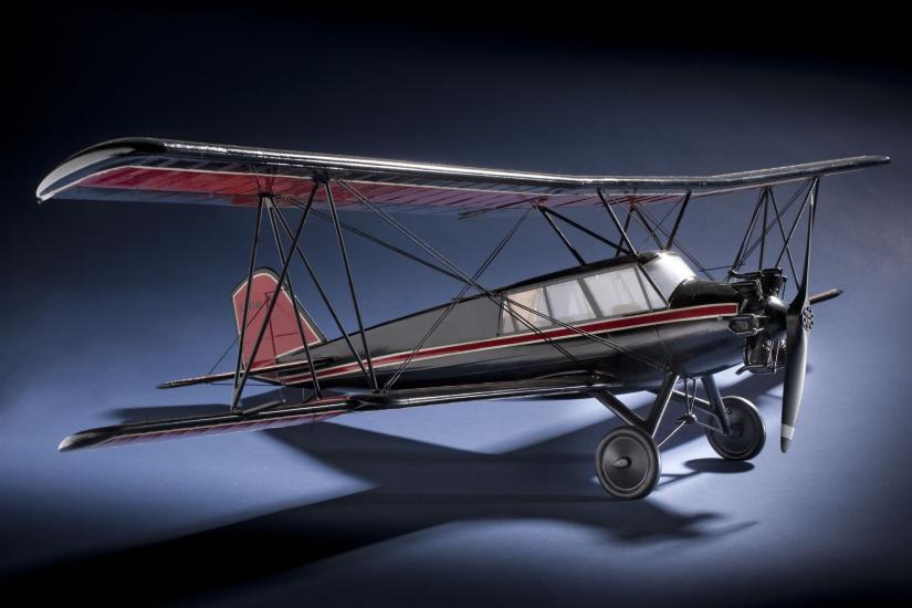 Side view of red and black biplane model with one engine. 