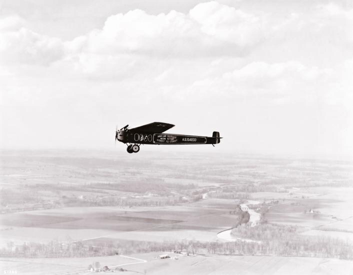 The T-2, a monoplane which attempted the first transcontinental flight, flies above land.