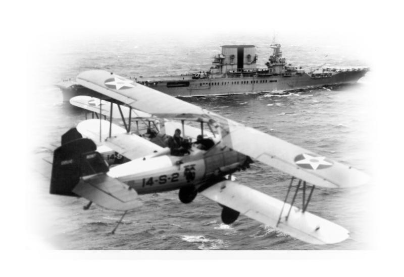 A military biplane flies over the ocean near an aircraft carrier.