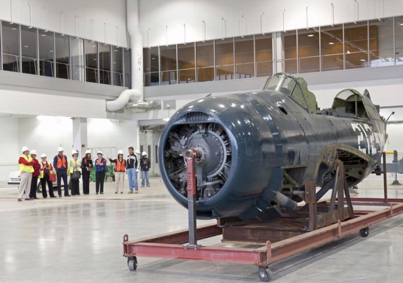 The fuselage of a blue military monoplane is the only aircraft inside the museum's restoration hangar.